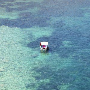 Little boat relaxing in the sea with heart towel as shade. Malta.