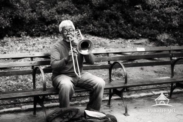 The Player 81 A New York City trombone player in Central Park on an autumn day. Black and white photograph.