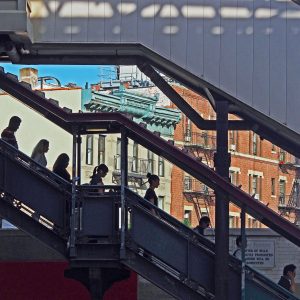 Commuters descend stairs from elevated train