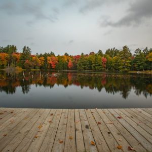 Fall colors reflected beyond the dock of Church Pond, Adirondacks NY