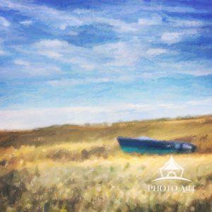 A small row boat in a field of gold against blue sky in Brittany, France.