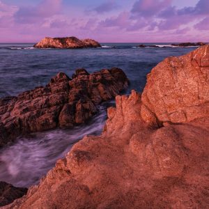 In the harsh light of mid-day, the granite shelf and formations at shoreline along Pebble Beach,