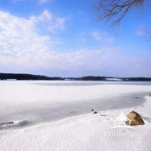 Snow and ice on Marsh Creek lake against bright blue sky in March in Pennsylvania.