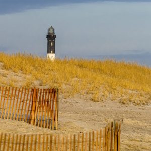 The Fire Island Ligjhthouse stands over a "golden hour" lit dune.