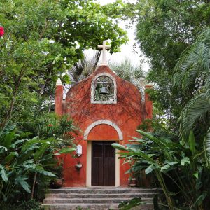 Cute little chapel facade in the midst of palms and trees at a hacienda in Merida, Mexico.