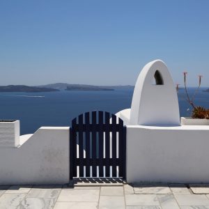 A blue gate entrance down to beautiful views of the pristine blue waters of Santorini, Greece.