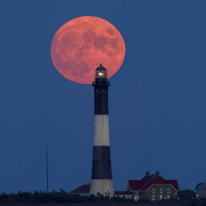Harvest moon dwarfs the Fire Island Lighthouse as it rises and the Lighthouse puts on it's own