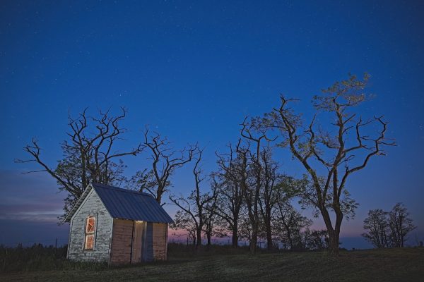 Storage shed located in cemetery.  Long exposure to capture stars with sunset in the background.