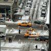 The photograph presents a wintery urban scene viewed from above. The street is covered in snow, with