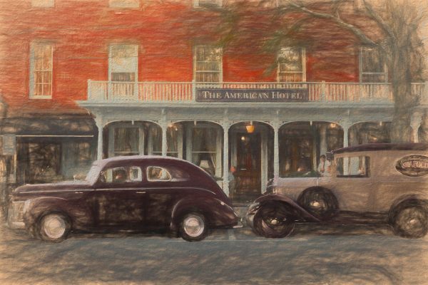This photo painting depicts the facade of the hotel with vintage vehicles parked in front.