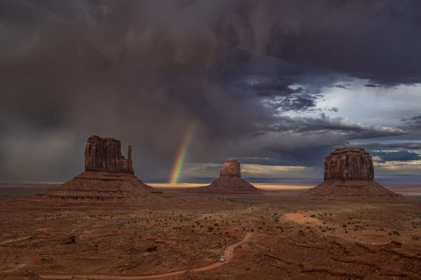 A rainbow a pairs during as a storm rolls across Monument Valley.
