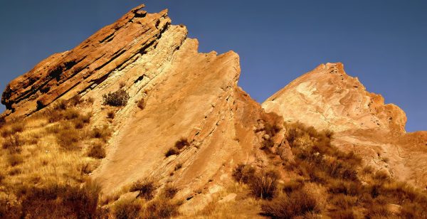 Majestic rock formations soar towards a clear sky, casting a warm hue in the sunlight. Sharp angles