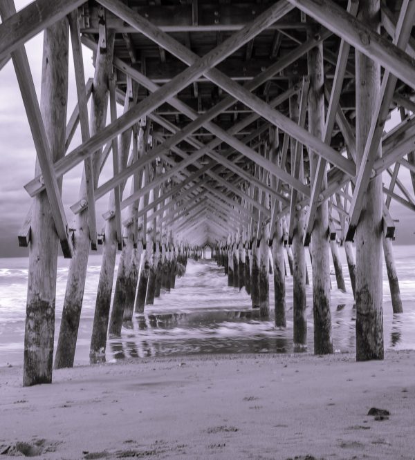 The old Folly Beach Pier going toward sunset. Watching the waves of the incoming tide breaking