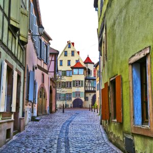 A charming cobblestone alleyway in Strasbourg, France, featuring a vivid green wall in the