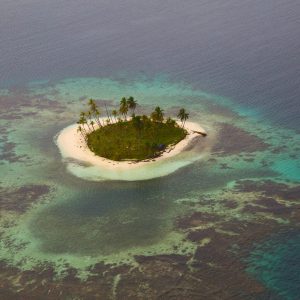 Aerial view of tiny island filled with palm trees. Off the coast of Panama. Near San Blas Islands.