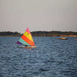 Cute, multi-colored sailboat passing by in the bay. Long Island, NY.