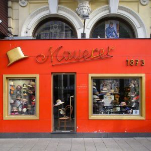 Hat store with vibrant orange storefront in downtown Vienna, Austria.