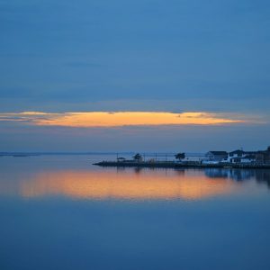 Sunlight peeping through the winter clouds, creating a glowy reflection in the water below.