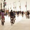 This is a photo painting showing a busy boardwalk with numerous people riding bicycles along the