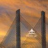 This is a photograph of the Kosciuszko Bridge against a dramatic sky. The bridge's tall, vertical