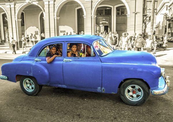 The artwork is a vibrant and dynamic photograph featuring a bright blue vintage car filled with
