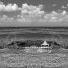 This is a panoramic photograph of a seascape. It depicts a calm yet slightly turbulent ocean with