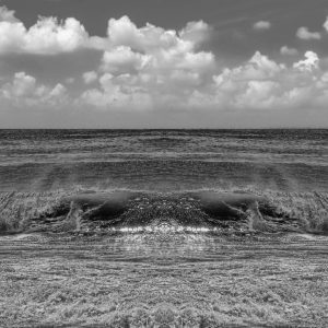 This is a panoramic photograph of a seascape. It depicts a calm yet slightly turbulent ocean with