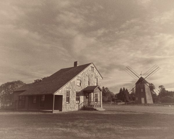 This sepia-toned photograph depicting the rustic, Gardner Mill Cottege Museum situated on its grassy
