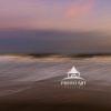 A tranquil sunset. The sky in hues of pink,purple, and orange. A long exposure was used to soften