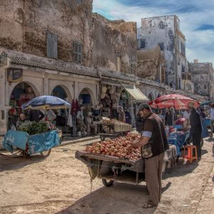 This image is a vibrant, detailed photograph capturing a bustling street market in Morocco. The
