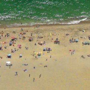 This is a photograph that captures an aerial view of a beach. The beach is bustling with many people
