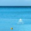 This is a photograph of a serene seascape featuring a solitary, brightly colored boat floating in
