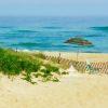 This is a photograph of a serene beach scene. The composition features golden sand dunes in the