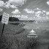 This black and white photograph captures a serene mooring pond scene. In the foreground, there is a