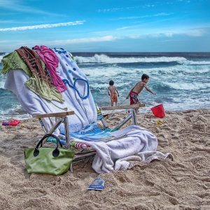 This photo depicts a vibrant beach scene. In the foreground, there are several colorful items,