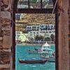  ﻿A vibrant Greek seascape is photographed through an old, rustic stone window frame. In the