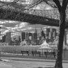 This black and white photograph is of the 59th St Bridge bridge and the skyline of a NYC. The