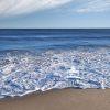 This a photograph depicting a serene beach scene. The image captures ocean waves gently rolling onto