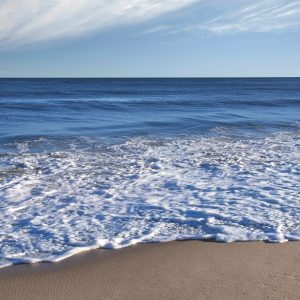 This a photograph depicting a serene beach scene. The image captures ocean waves gently rolling onto