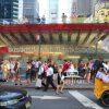 This a photograph capturing a bustling urban scene with a large crowd of people gathered at a busy