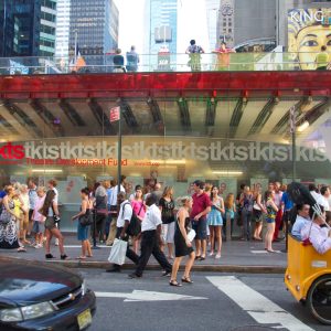 This a photograph capturing a bustling urban scene with a large crowd of people gathered at a busy