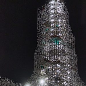 The spire scaffolding tops out in the darkness, but the work goes on 24/7.