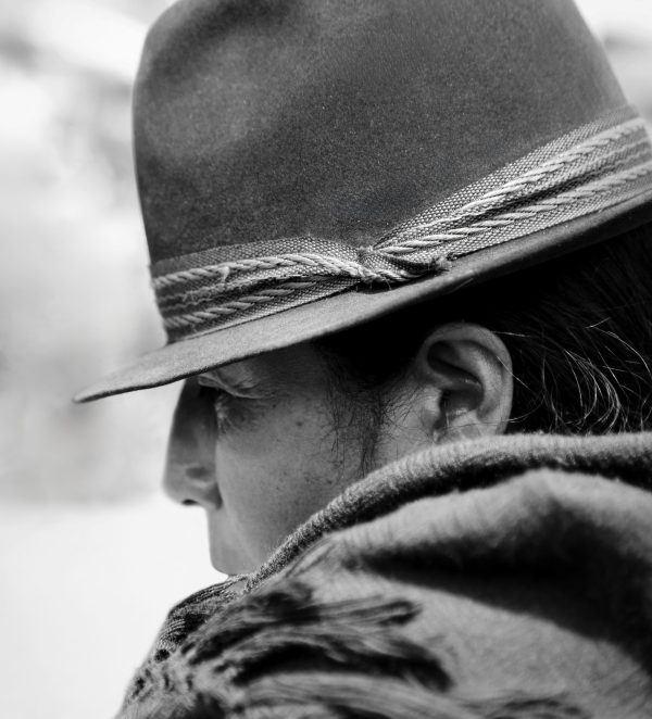 A black-and-white profile of an Ecuadorian woman at the Otavalo market, her expression reflecting