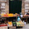 The artwork is a vibrant photograph depicting a street market scene with a rustic and textured stone