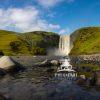 Skógafoss waterfall cascades powerfully over a 200- foot cliff, its white curtain of water