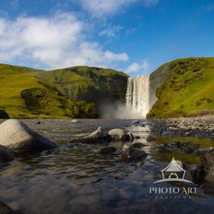Skógafoss waterfall cascades powerfully over a 200- foot cliff, its white curtain of water
