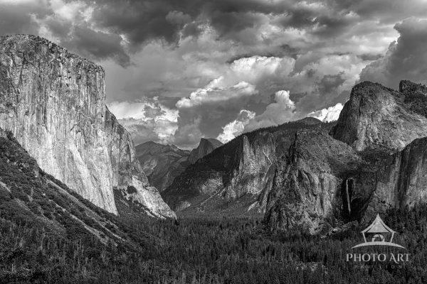 A stunning black and white view of Yosemite Valley with towering granite cliffs and dramatic cloud