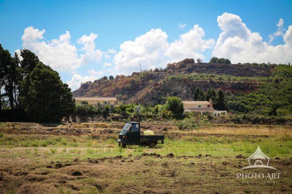 A lone Piaggio Ape rests in the hot countryside of Calabria, captured along the winding road to
