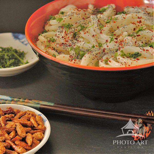 Noodles become a small sanctuary of warmth and comfort surrounded by humble companions completing