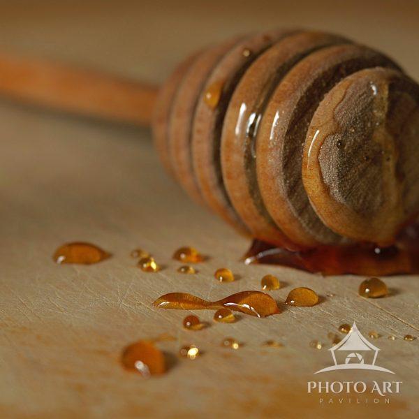 Honey drizzler holding the last of amber sweetness. The droplets gather slow and deliberate towards